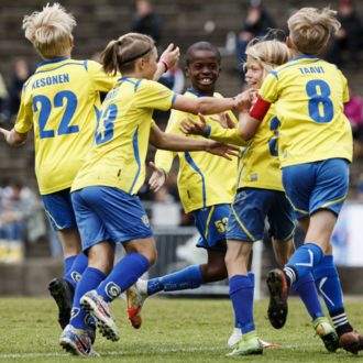 Five children in soccer uniforms celebrate after a goal.